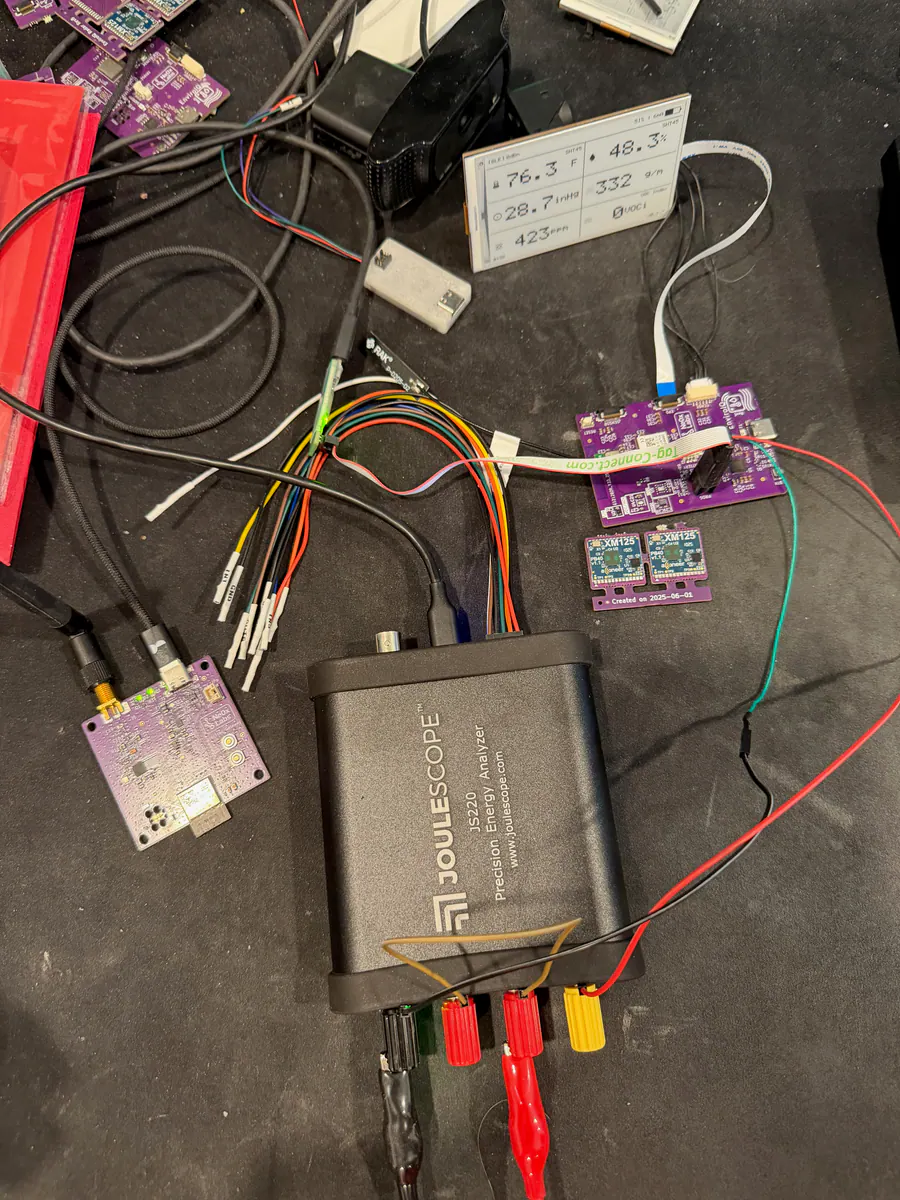 EnviroIQ bench setup with e-ink display, JouleScope JS220, SimpleAir boards, wiring, and XM125 radar modules.